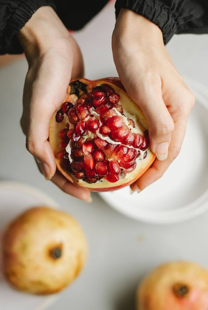 Female hands hold a broken open pomegranate.