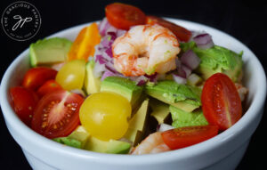 Shrimp and avocado salad mixed together in a white mixing bowl.