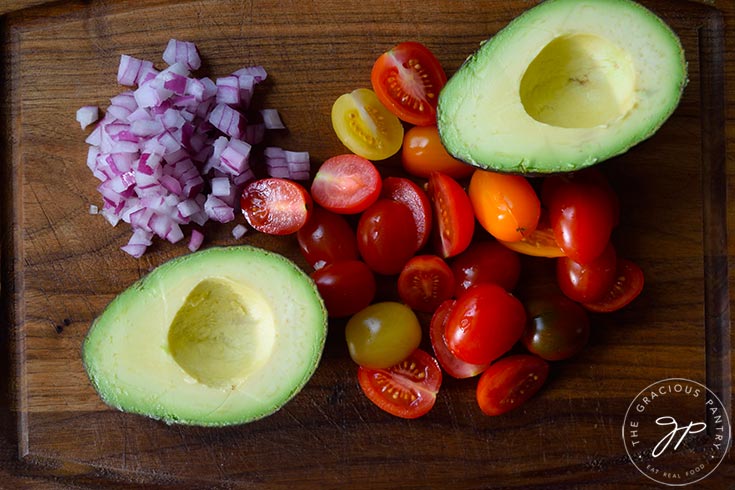 Shrimp and avocado salad recipe ingredients sitting on a cutting board.