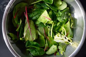 Kale and mixed greens laying in a metal mixing bowl.