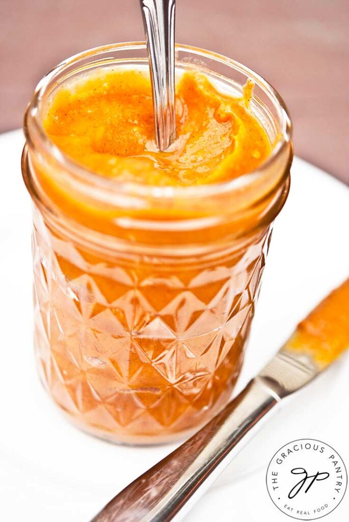 Sweet Potato Butter in a glass jar with the lid off and a spoon handle sticking out of it.