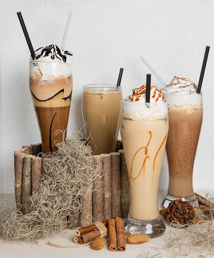 Four blended drinks topped with whipping cream and chocolate sauce or caramel.
