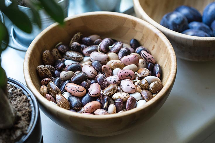 This list of superfoods includes beans. This photo shows a wooden bowl filled with various dried beans.