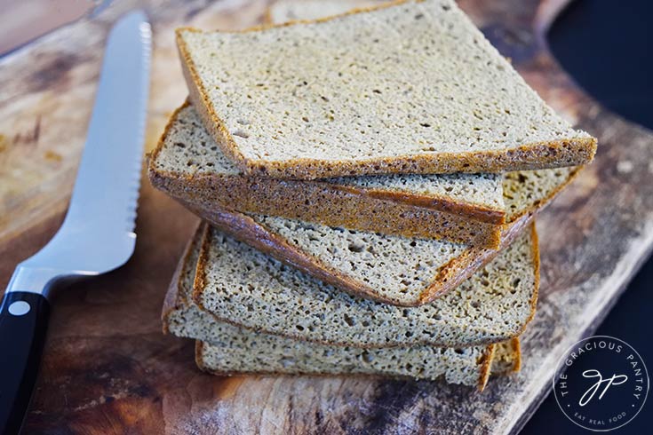 A stack of just-sliced chicken bread sitting on a wood cutting board.