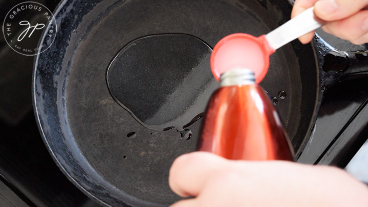 Measuring oil into a cast iron skillet.