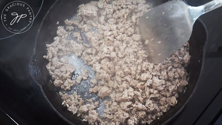Ground turkey cooking in a cast iron skillet.