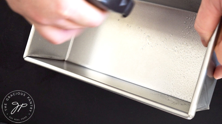 Spraying a standard loaf pan with an oil sprayer.