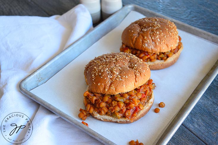 Two Lentil Sloppy Joes sit on a parchment lined baking pan.