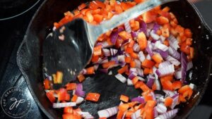 Sautéing bell peppers and onions in a skillet.