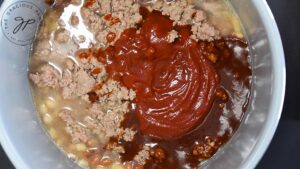 Ketchup, barbecue sauce and browned meat added to beans in a crock.