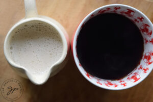 Just-made French vanilla coffee creamer in a pitcher sitting next to a mug of coffee.