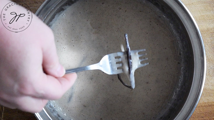 Removing the vanilla bean pod from a pot of coffee creamer.