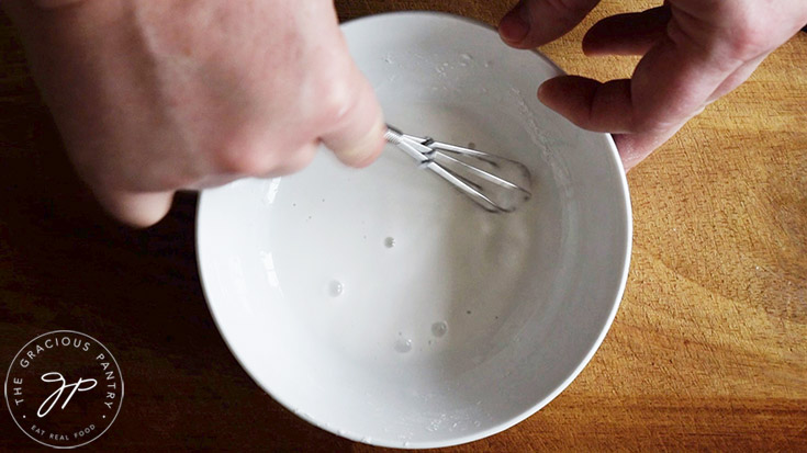 Whisking slurry in a white bowl.