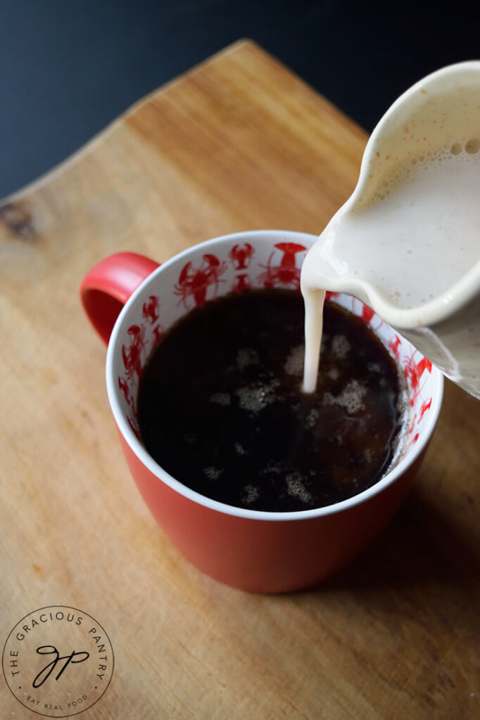 Pouring French vanilla coffee creamer into a mug of coffee.