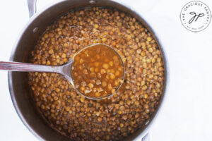 A ladle lifts some just-cooked German Lentil Soup out of a pot.