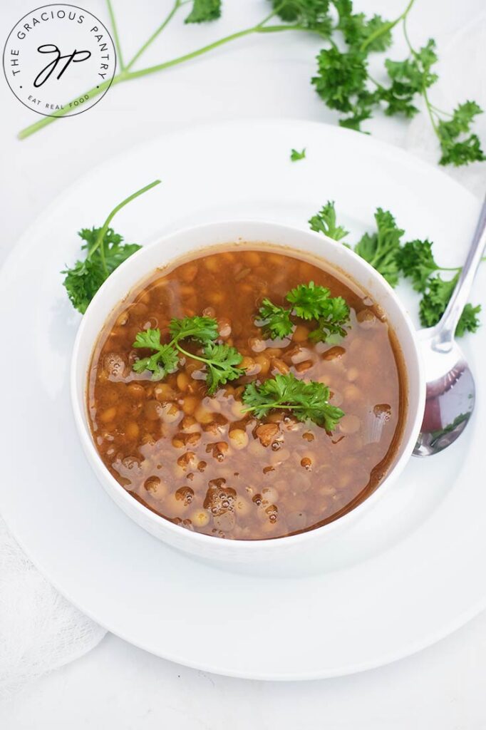 A white bowl filled with German Lentil Soup and garnished with fresh parsley.