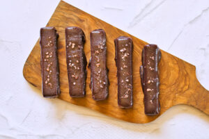 Healthy Twix Bars covered in chocolate and laying on a cutting board.