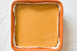 Peanut butter spread over Healthy Twix Bars crust in a baking pan.