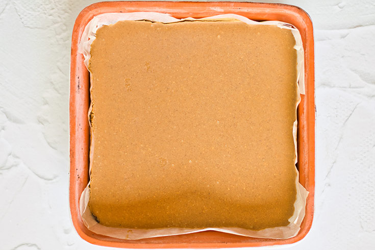 Frozen peanut butter spread over Healthy Twix Bars crust in a baking pan,, just out of the freezer.