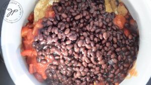 Black beans and diced tomatoes added to chicken, spices and chopped onions in a slow cooker.
