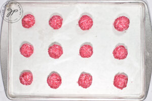 Scoops or balls of Raspberry Coconut Truffle fiilling on a parchment-lined baking pan.