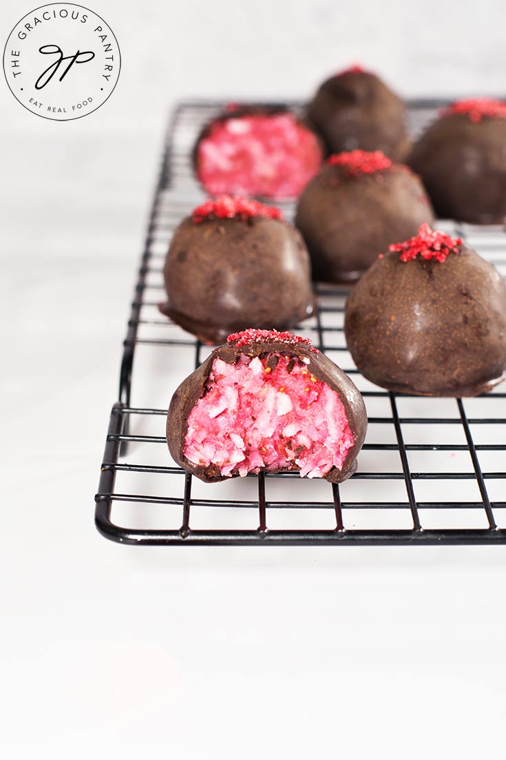 Raspberry Coconut Truffles sitting on a cooling rack, dusted with rapsberry powder.