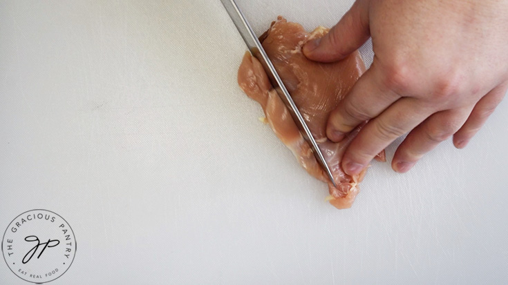 Slicing a chicken thigh into strips.