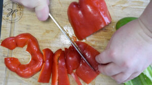 Slicing bell peppers into thick strips.