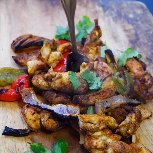 Finished Sheet Pan Fajitas on a cutting board.