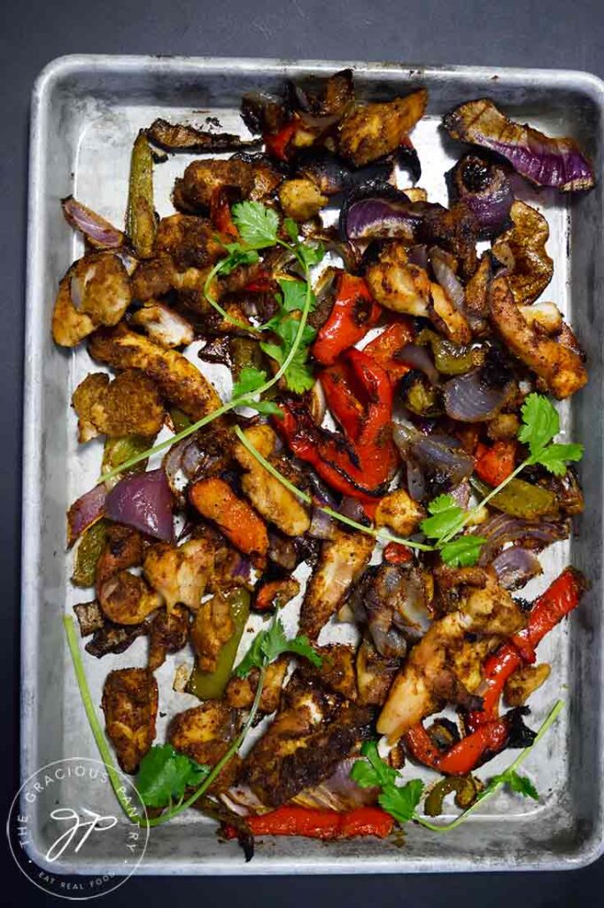 An overhead view of chicken and veggies on a baking pan.