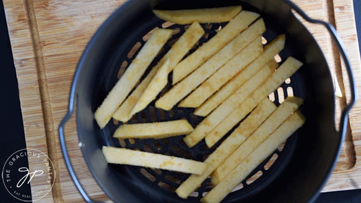 Fries placed in a single layer in an air fryer basket.