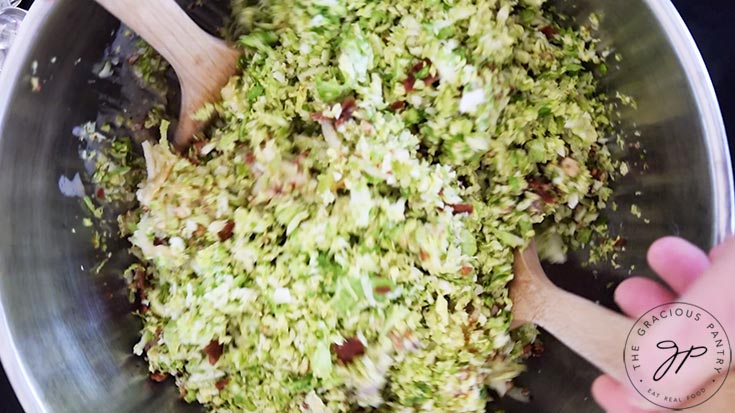 Tossing the Brussels Sprouts Salad in a large mixing bowl.