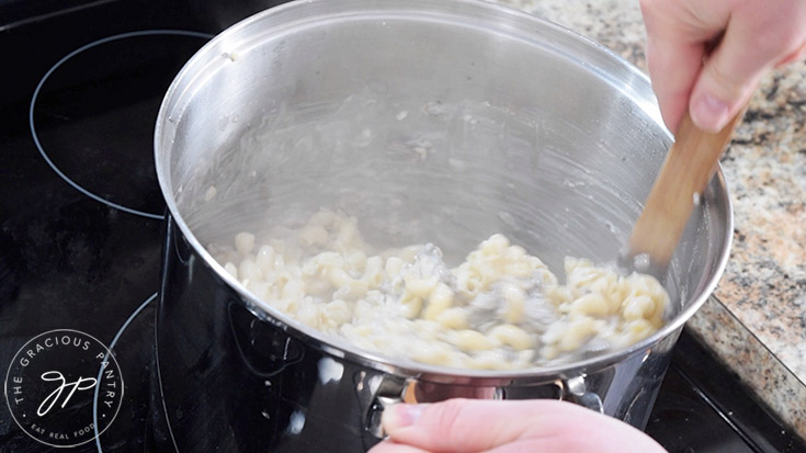 Mixing together the Creamy Garlic Mushroom Pasta sauce and pasta in a large pasta pot.