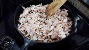 Raw mushrooms added to a warmed skillet with oil.