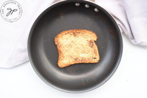 A slice of french toast cooking in a skillet.