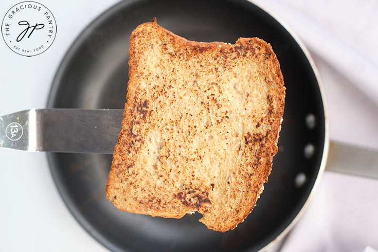 A finished piece of french toast being held up by a spatula.