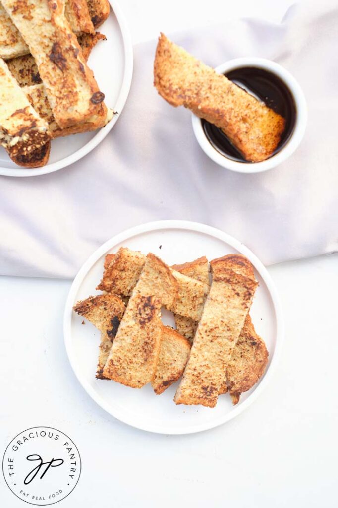 A French Toast Stick sitting in a small bowl of maple syrup.