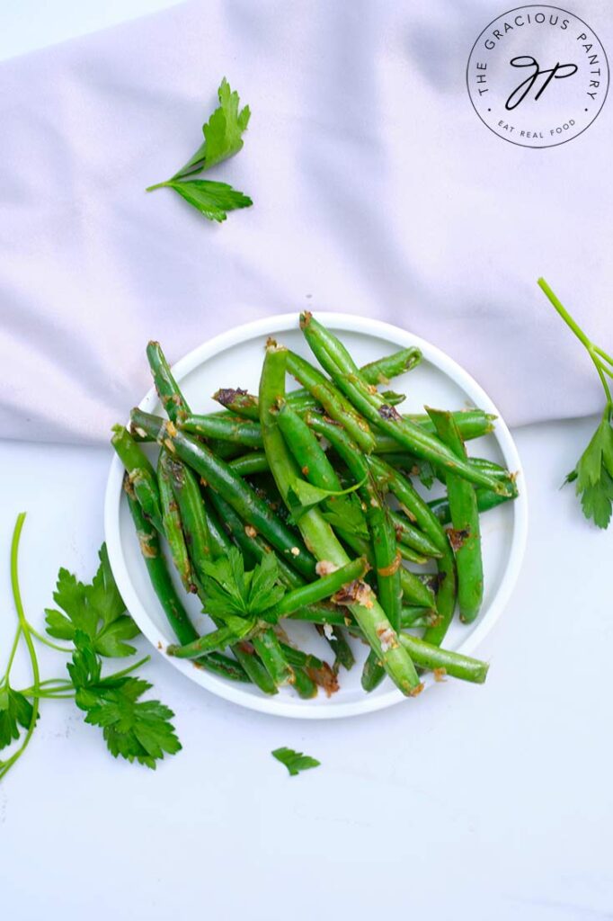 Garlicky Green Beans fill a white plate on a white background.