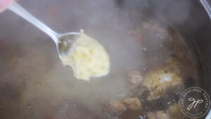 A spoon picks up a small amount of the smashed potatoes.