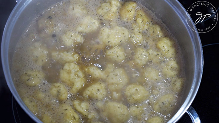 Dumplings floating at the top of a boiling pot of German Potato Dumpling Soup.