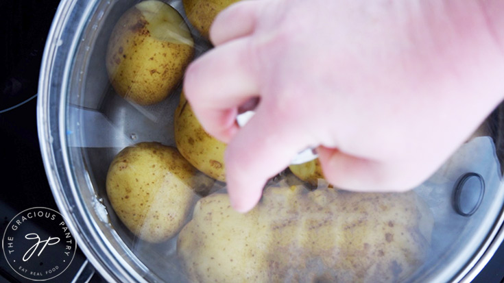 Placing a lid on a pot of salt water and potatoes.