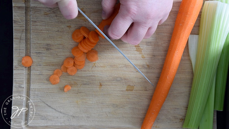 Slicing carrots on a wooden cutting board.