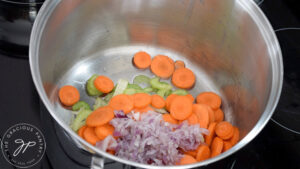 Raw, sliced carrots, celery and onions in oil in a large soup pot.