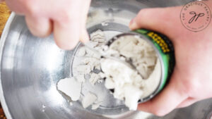 Adding coconut cream to a mixing bowl.