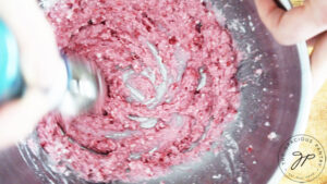Blending raspberry frosting in a mixing bowl.