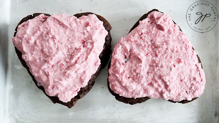 Raspberry frosting spread over the top of two Healthy Chocolate Raspberry Cakes.