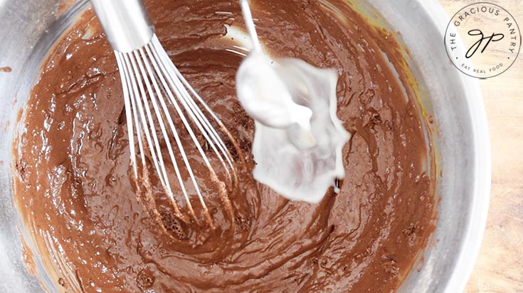 Adding some milk to the Healthy Chocolate Raspberry Cake batter for consistency.