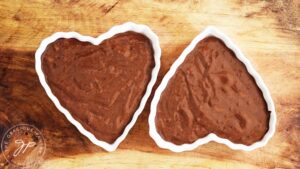 Two heart-shaped ramekins filled with Healthy Chocolate Raspberry Cake batter.