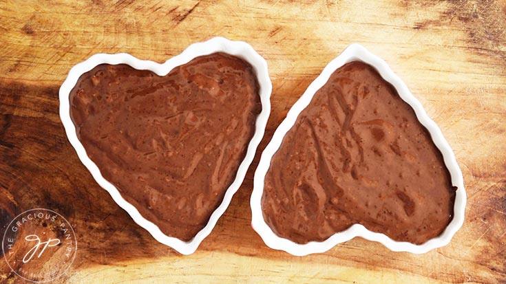 Two heart-shaped ramekins filled with Healthy Chocolate Raspberry Cake batter.