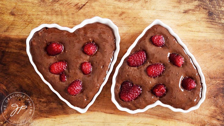 Healthy Chocolate Raspberry Cake batter in ramekins with fresh raspberries pressed into it.